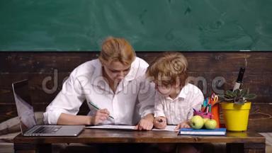 和老师一起微笑的孩子。 教室里黑板桌附近的男孩。 孩子准备上学了。 教师节。 孩子学习
